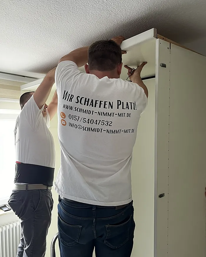 Zwei Leute von Schmidt nimmt mit bauen einen Kleiderschrank ab