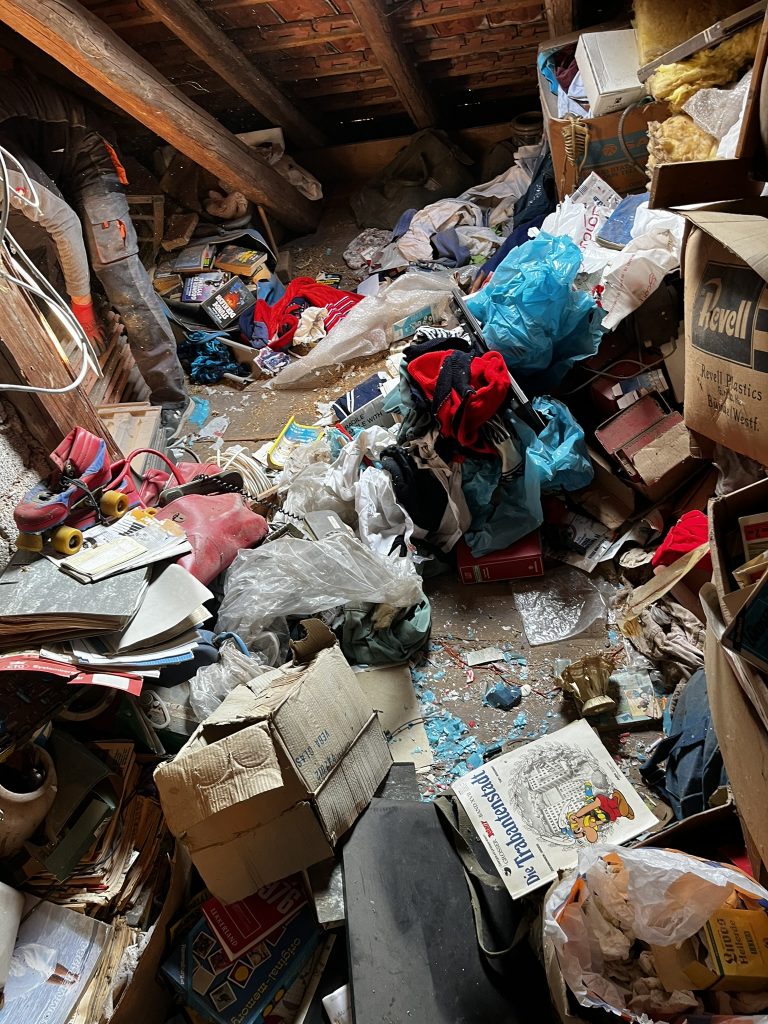 Überfüllter Dachboden vor der Entrümpelung in Bad Kreuznach und Umgebung. Kartons, Kleidung und verschiedene Gegenstände stapeln sich chaotisch.